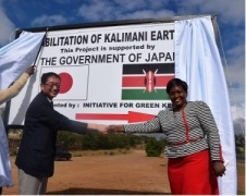 H.E. Mr. Tatsushi Terada and Ms. Martha Mulwa shaking hands in front of the signboard