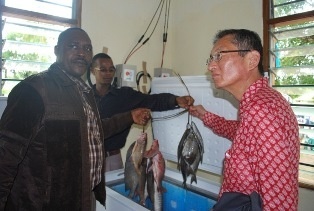 H.E.Tatsushi Terada holding fish from the solar chest freezer