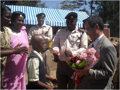 Deputy Ambassador receiving a bouquet of flowers from a pupil at the home at the start of the ceremony