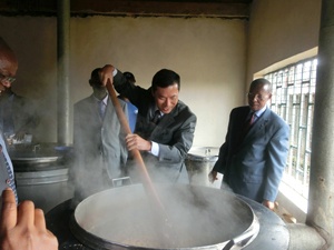 給食の調理を手伝う高田大使(右はキロンゾ教育大臣)。 調理担当者は毎朝6時台から作業を始めます。