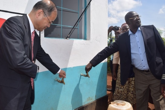 Mr. Katayama opening the tap at the water kiosk with H.E. Mr. Rasanga